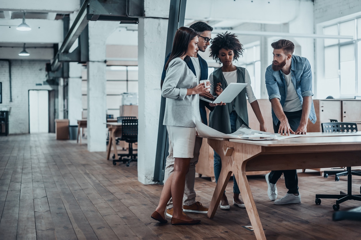 Group of young business people working together in creative office while standing near the wooden desk