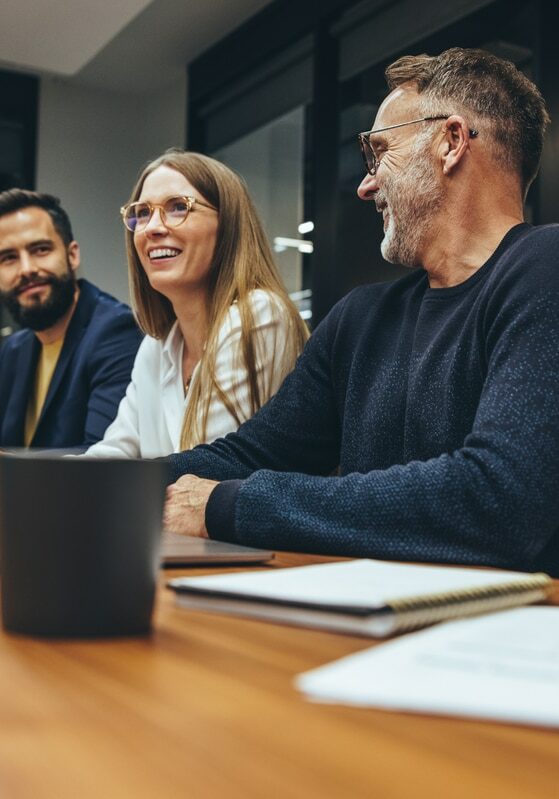 Successful group of businesspeople having a briefing in a boardroom. Happy businesspeople smiling while working together in a modern workplace. Diverse business colleagues collaborating on a project.